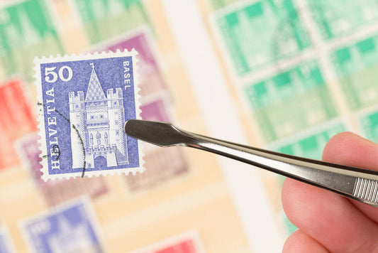 Tweezers holding a vintage Helvetia 50 stamp over a blurred stamp collection